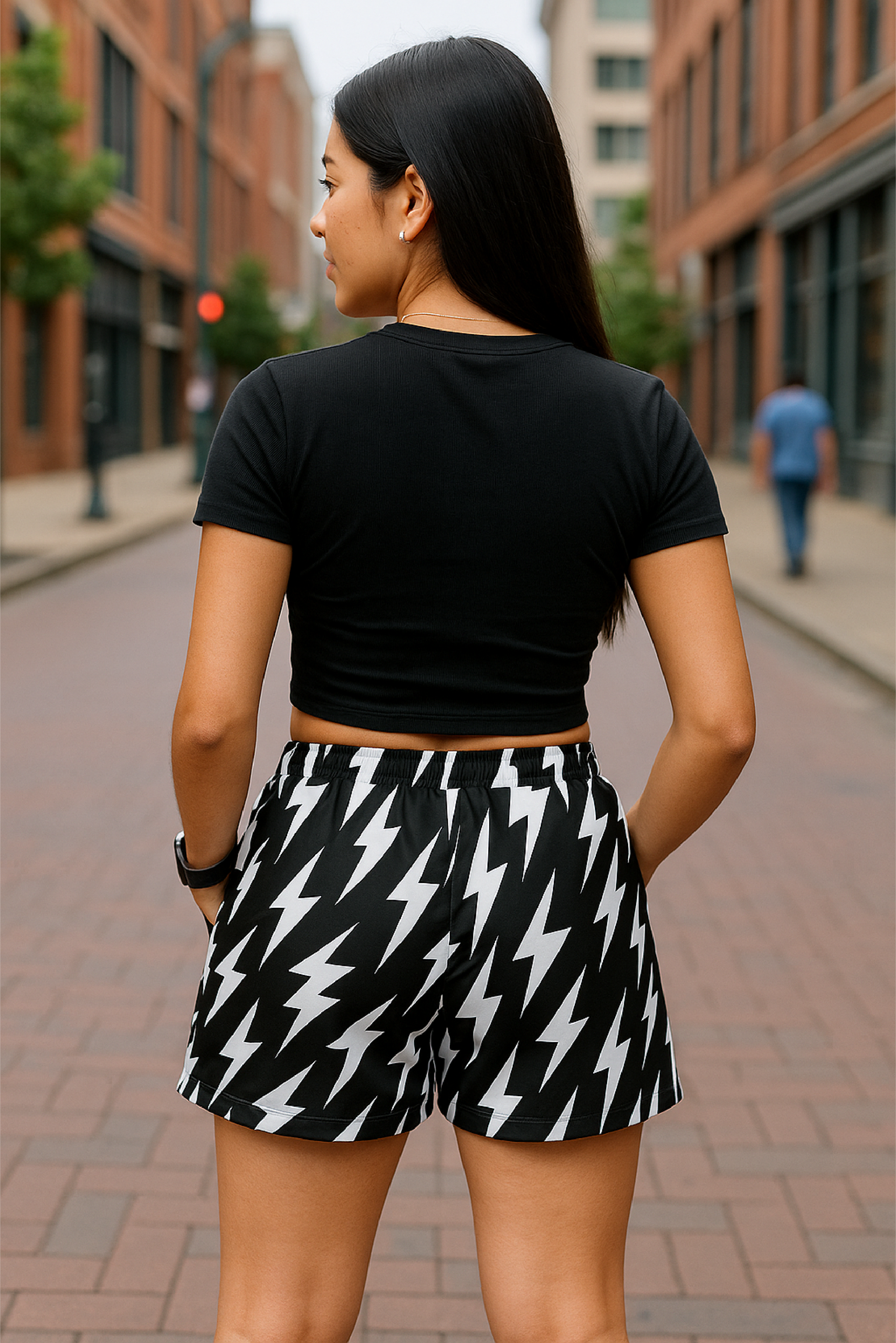 Woman wearing a black crop top and black and white lightning bolt patterned shorts on a city street.