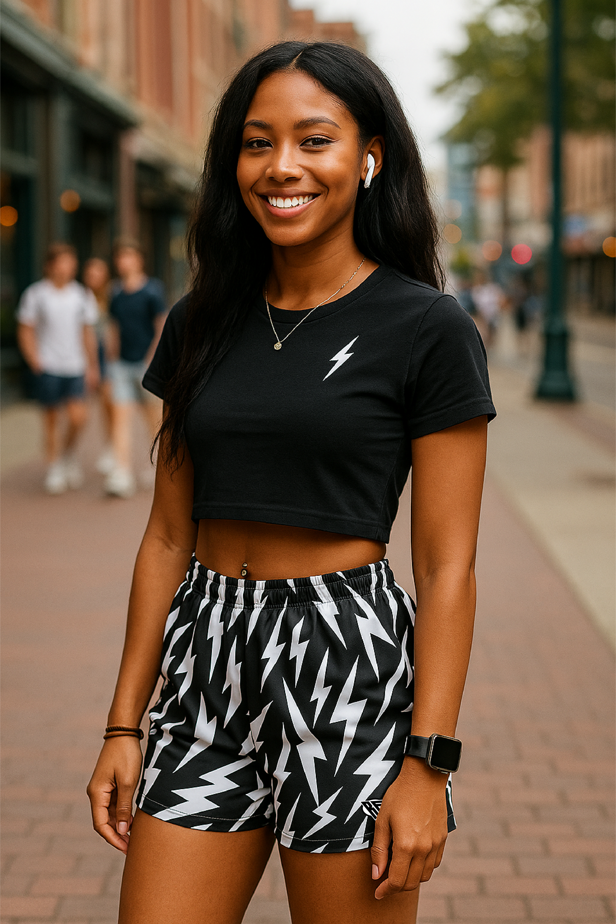 Woman wearing a black crop top with a lightning bolt design and black and white lightning bolt patterned shorts on a city street.