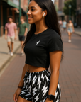 Woman wearing a black crop top with a lightning bolt design and black and white lightning bolt patterned shorts on a city street.