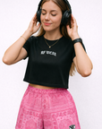 Woman listing to music from headphones wearing a black top and RF-Wear Women's Bandana Mismatch Pocket Shorts in Pink