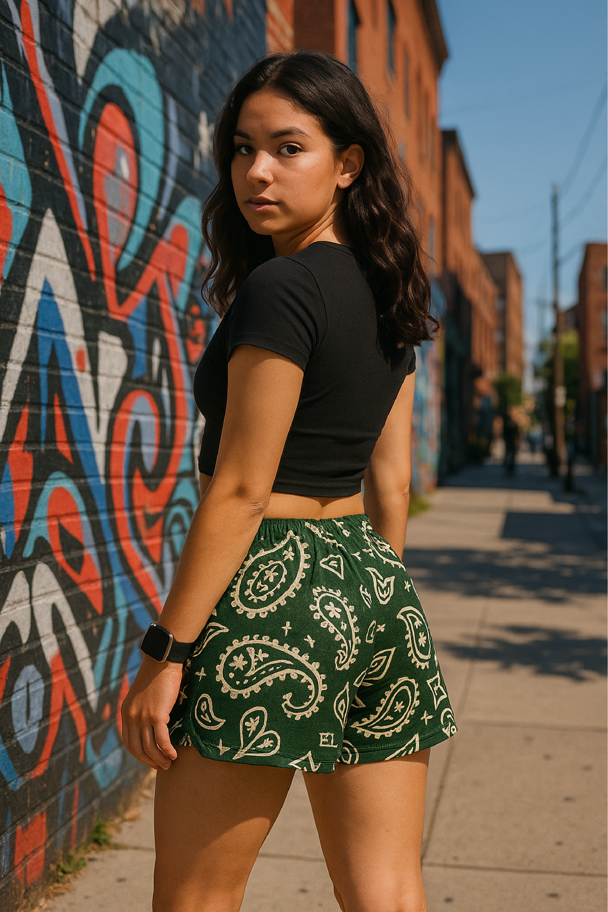 Woman standing on sidewalk wearing RF-Wear Women's Paisley Shorts - Pine/Cream - Back View