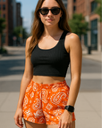 Woman on city street wearing RF-Wear Women's Paisley Shorts - Orange /White - Front View