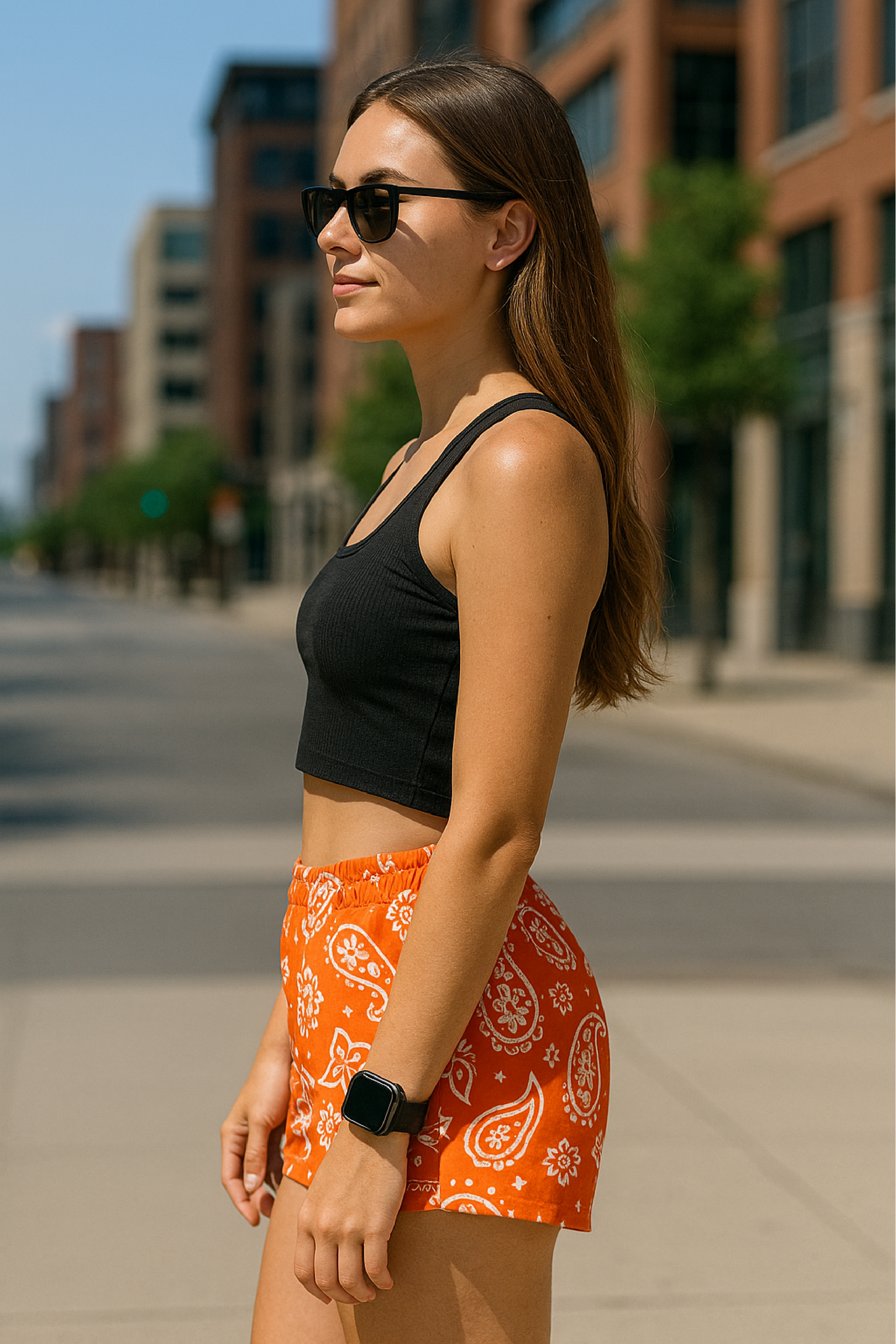 Woman standing on street in city wearing RF-Wear Women's Paisley Shorts - Orange /White - Side View