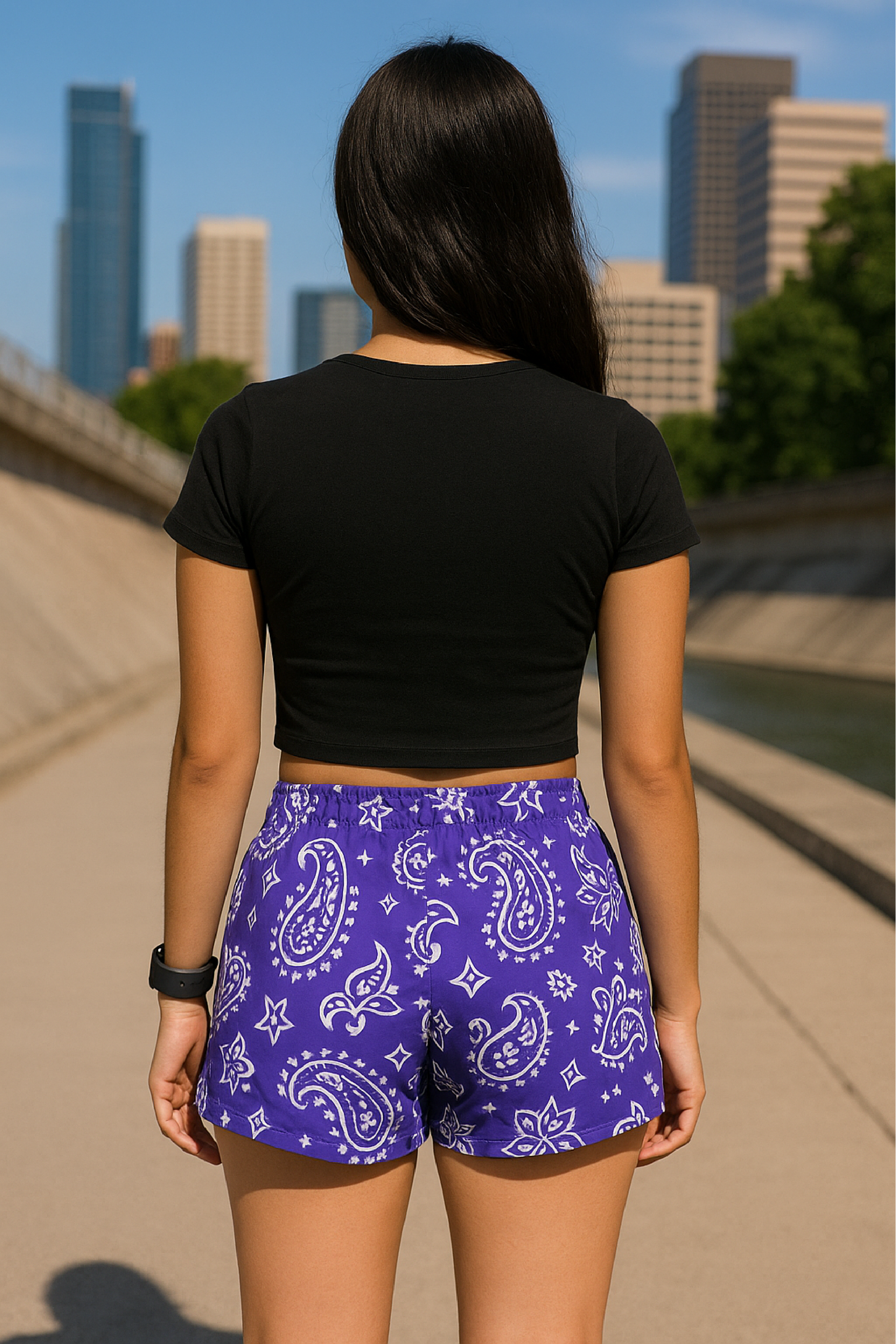 Woman standing on city sidewalk wearing RF-Wear Women's Paisley Shorts - Purple/White - Back View