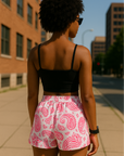 Woman on city sidewalk wearing RF-Wear Women's Paisley Shorts - White/Fuchsia - Back View