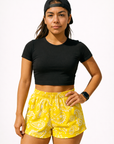 Woman wearing a black top and RF-Wear Women's Paisley Shorts in Yellow/White 