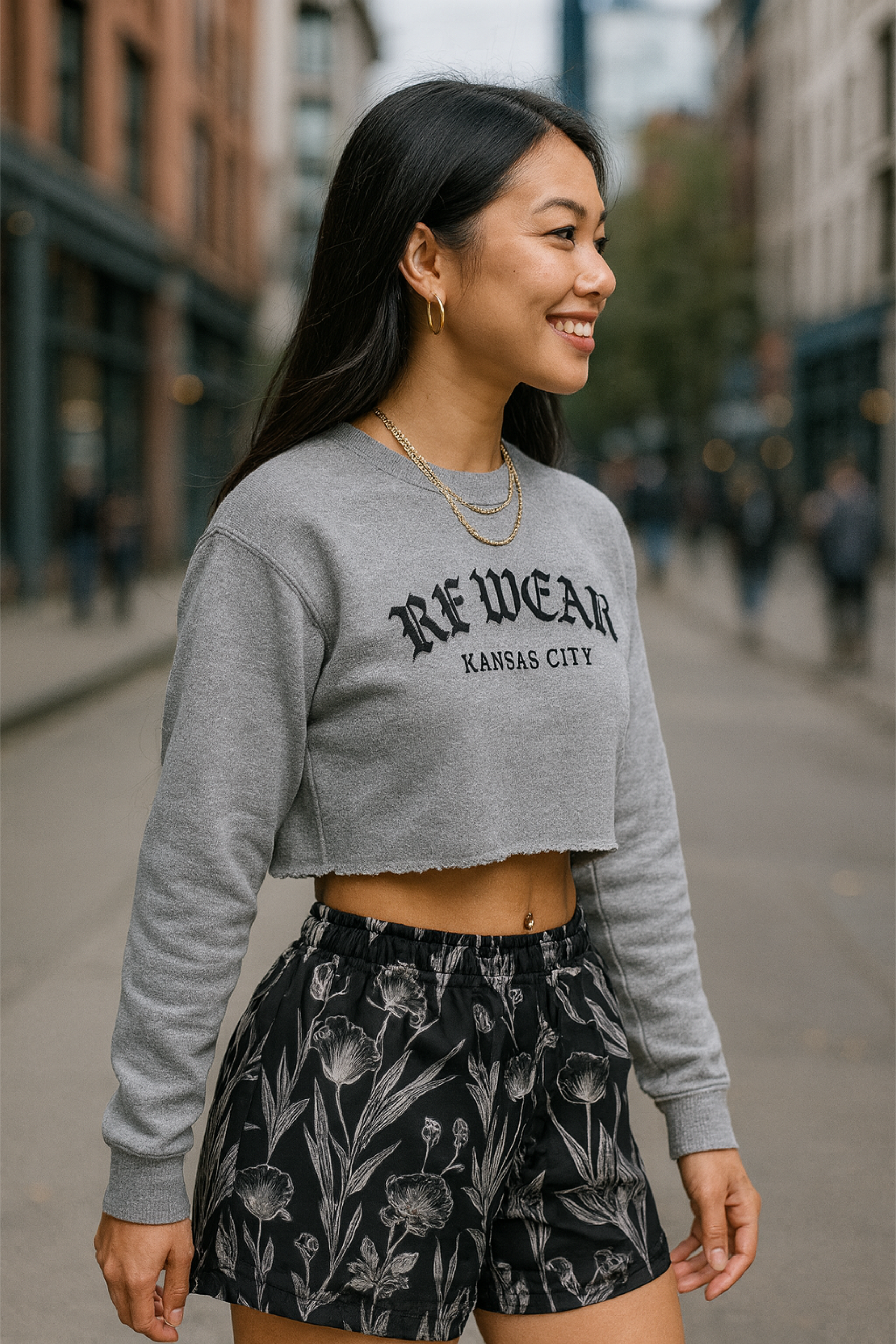 Woman wearing a gray sweatshirt with 'RF-WEAR' branding and RF-Wear women's black/grey  porcelains shorts on a city street.