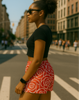 Woman in black top and RF-Wear women's rose shorts in red/white standing on a city street.