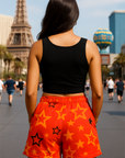 Person wearing black top and orange shorts with star pattern in an urban setting