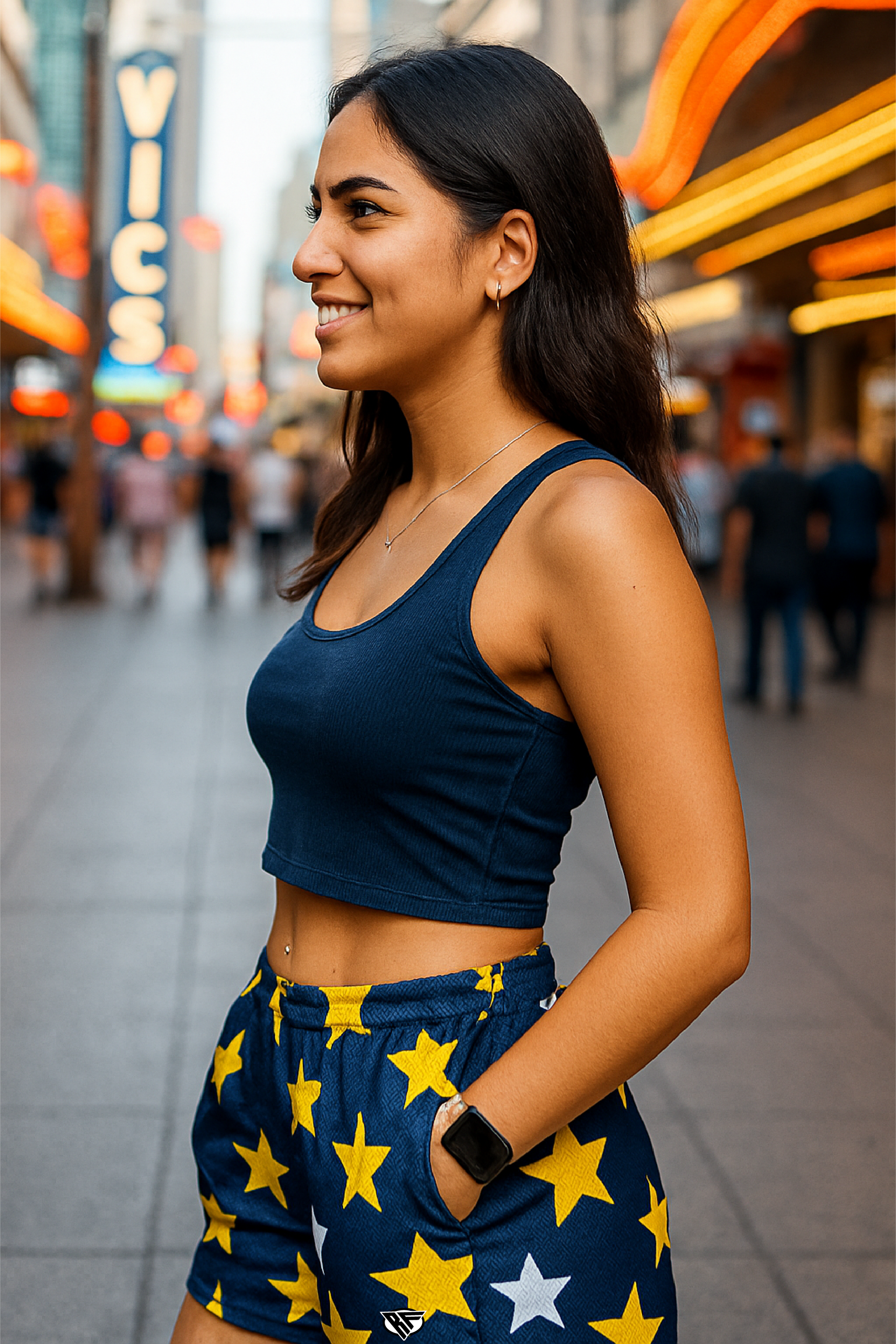 Woman in a blue top and star-patterned shorts standing on a city street with blurred background