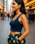 Woman in a blue top and star-patterned shorts standing on a city street with blurred background