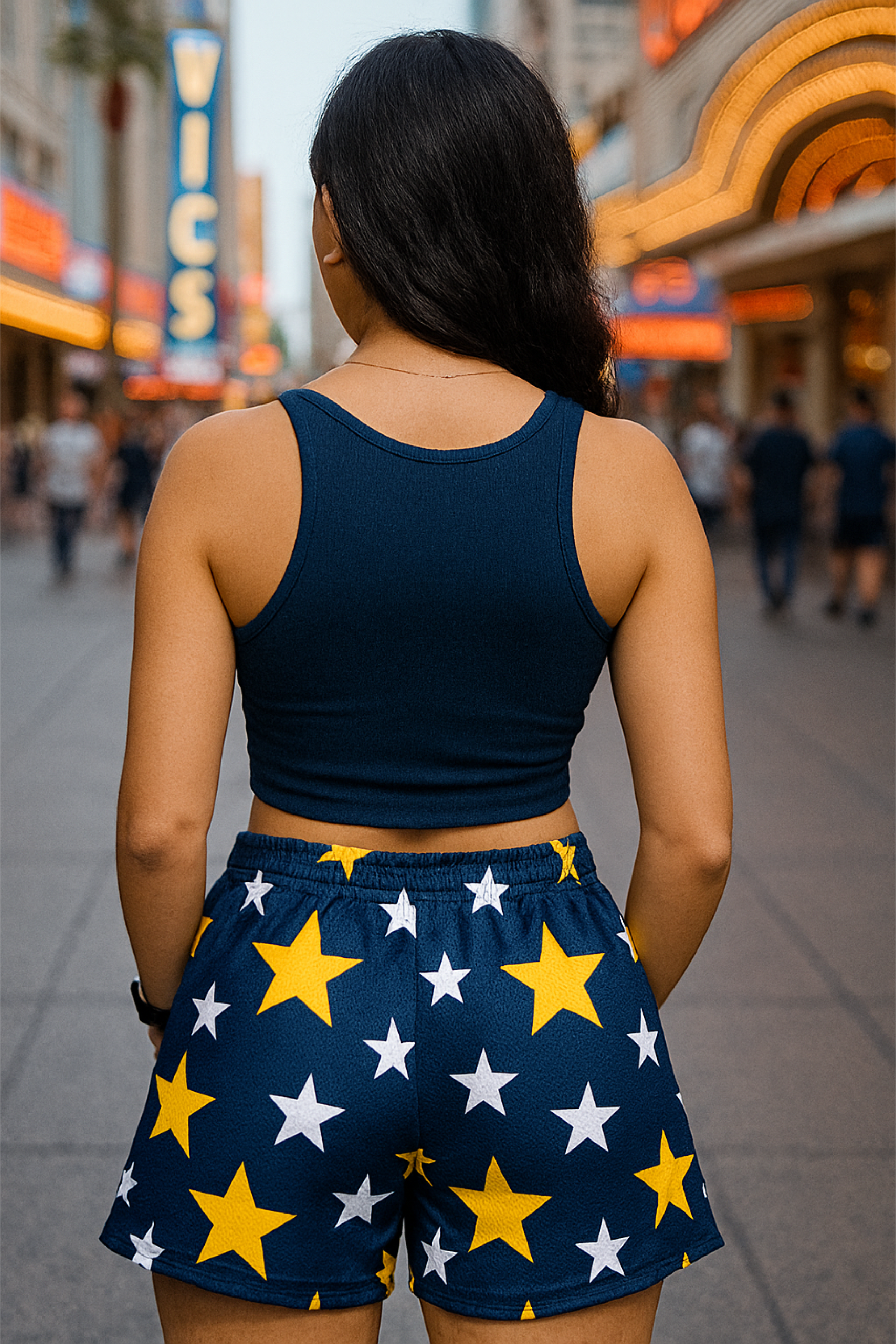 Woman wearing a navy blue tank top and shorts with star pattern on a city street.