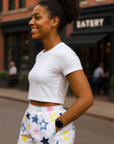 Woman wearing a white crop top and star-patterned shorts on a city street.