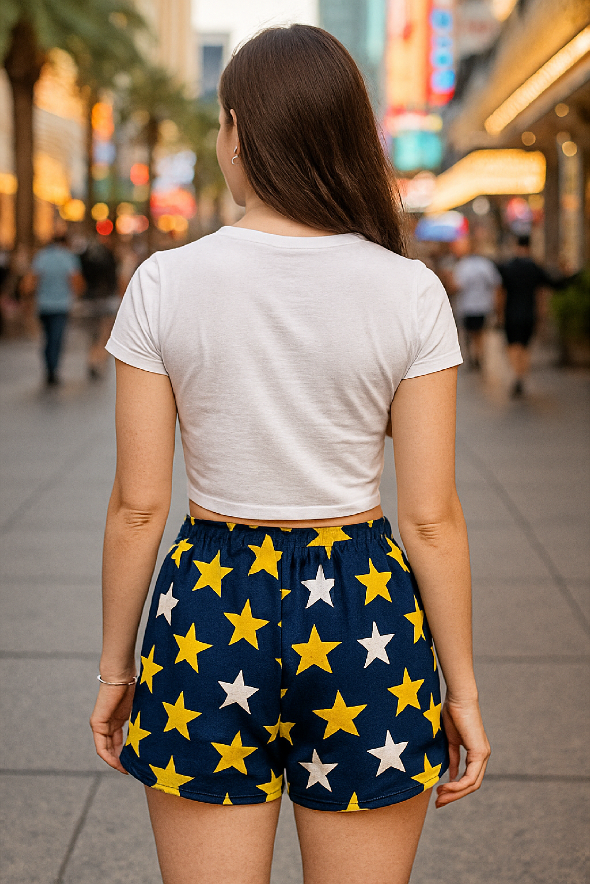 Person wearing a white t-shirt and star-patterned shorts on a city street.