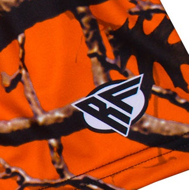 Close-up of orange tree camo shorts with a brand logo