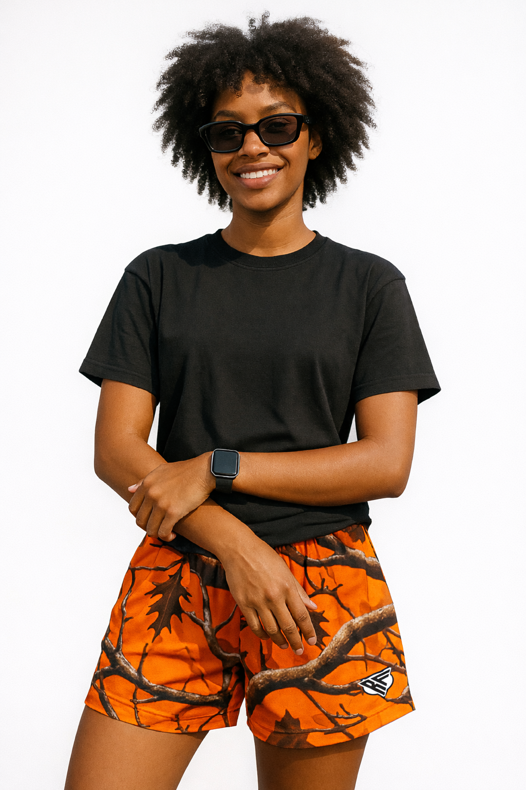 Woman wearing a black top and RF-Wear Women's Tree Camo Shorts in Orange 