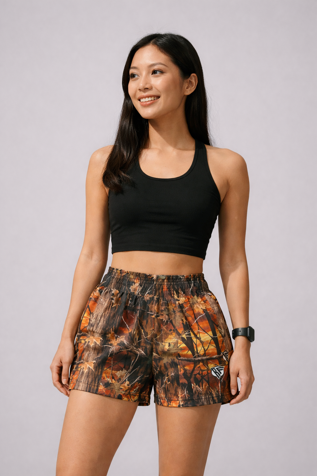 Woman wearing a black top and RF-Wear Women's Tree Camo Shorts in Sunset