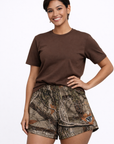 Woman wearing a brown top and RF-Wear women's  tree Camo shorts in tan