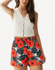 Woman wearing a white top and RF-Wear Women's Tropical Flower Shorts in Coral on Black/White