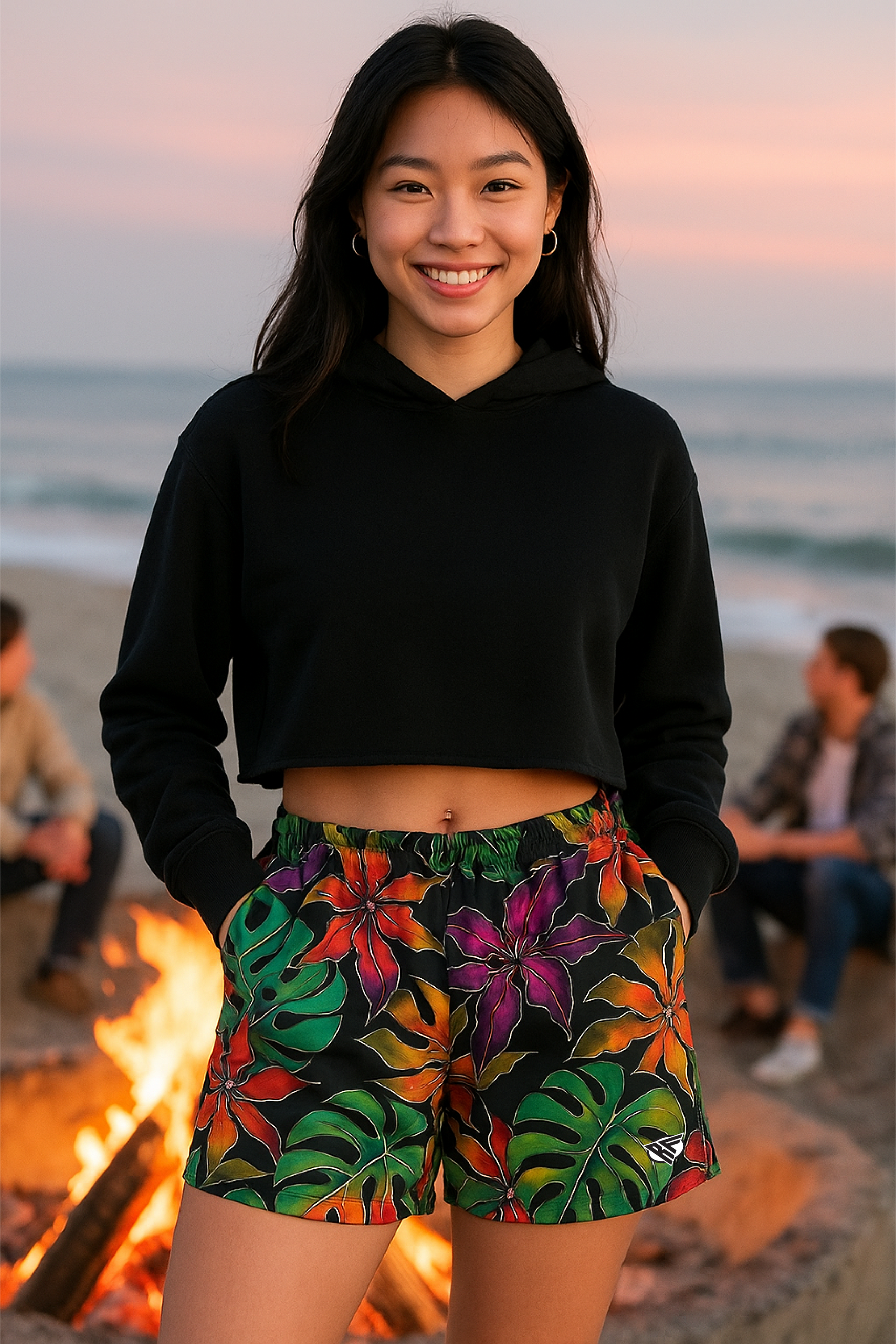 Woman wearing a black crop top and colorful floral shorts on a beach.