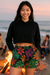 Woman wearing a black crop top and colorful floral shorts on a beach.