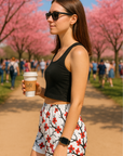 Woman holding a coffee cup with cherry blossom trees in the background wearing a black top with RF-Wear Women's Blossom shorts in White/Burgundy