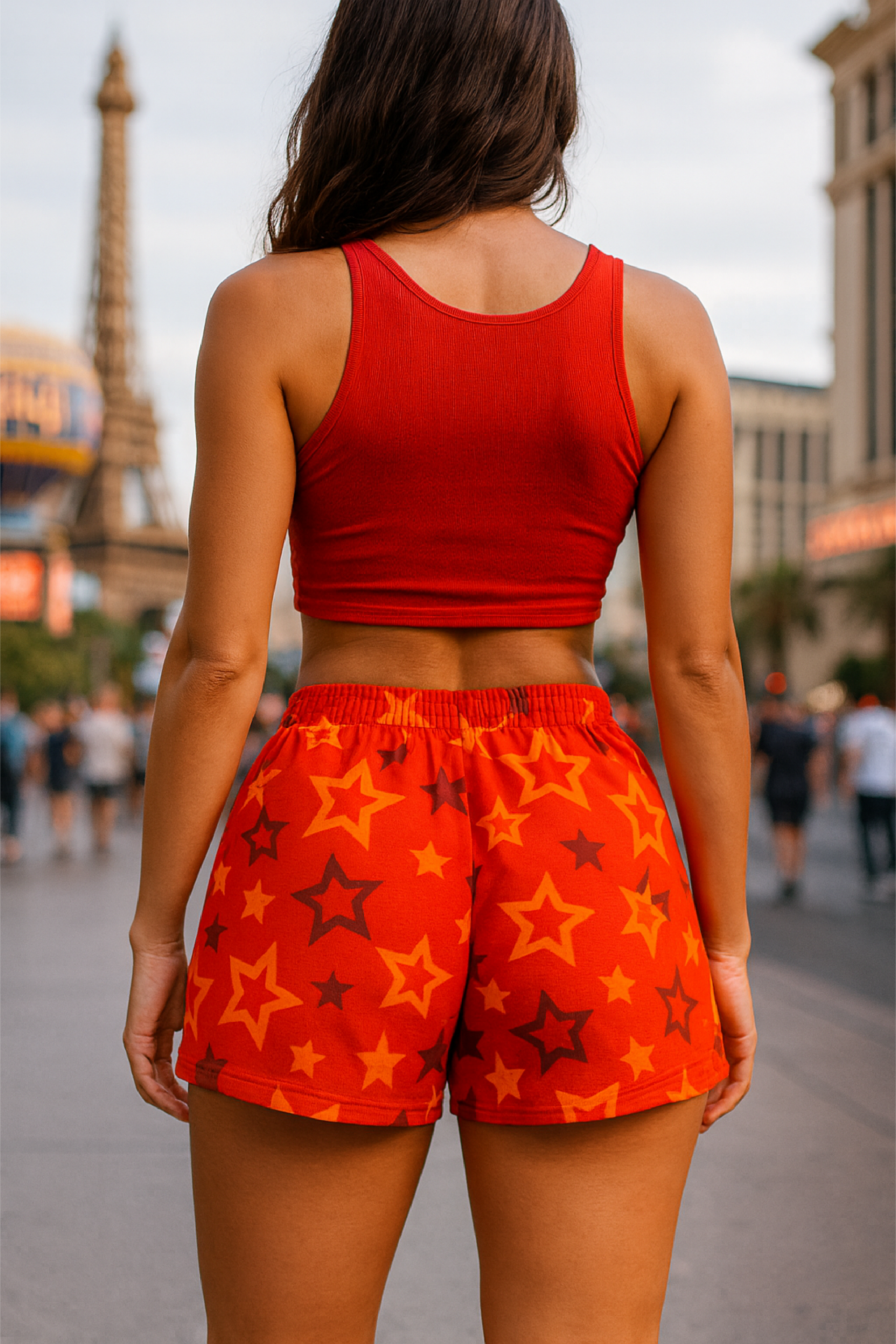 Person wearing a red tank top and orange shorts with star pattern in an urban setting