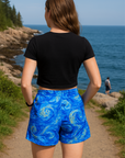 Person wearing blue shorts with a starry night design by the ocean