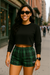 Woman wearing a black crop top and green plaid shorts on a city street.