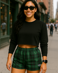 Woman wearing a black crop top and green plaid shorts on a city street.